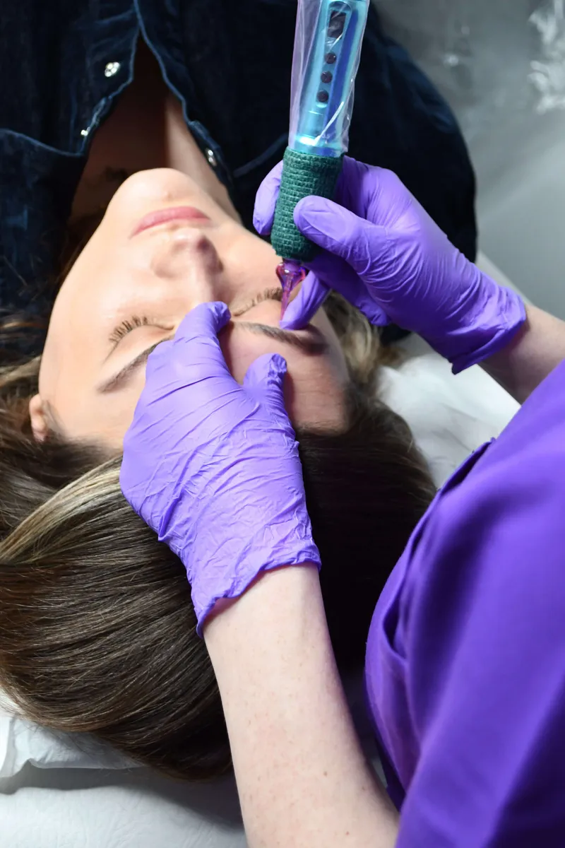 Close-up of Linda using a digital device to create combination brow hair strokes and shading