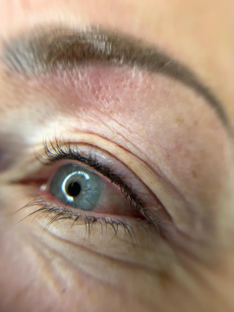 Close-up of an eye showing permanent eyeliner tattooed along the lash line